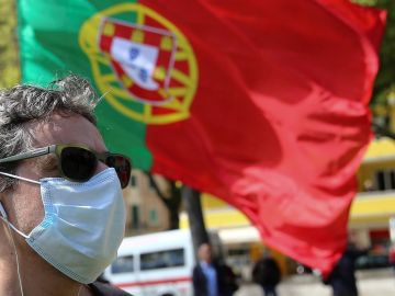 Un ciudadano pasa por delante de una bandera de Portugal