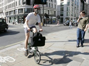 Un londinense se dirige a trabajar en bicicleta con mascarilla en la cara en Londres, Reino Unido.