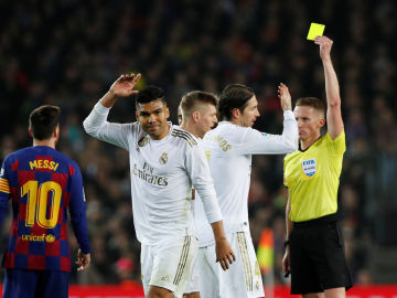 Los jugadores del Real Madrid protestan una amonestación de Hernández Hernández en el Clásico