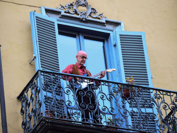 Un hombre toca la guitarra en su balcón, en una ciudad italiana
